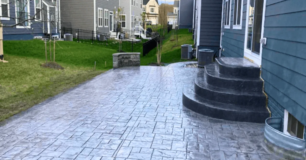 Stamped concrete walkway and curved steps running alongside a house between neighboring homes