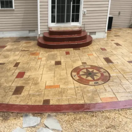 Stamped concrete patio with a decorative compass-rose inlay and a contrasting red border