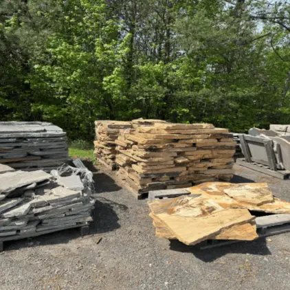 Pallets of flat natural stone slabs stacked in a gravel supply yard