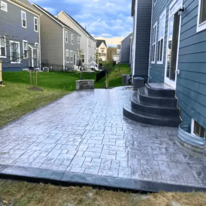 Stamped concrete walkway and curved steps running alongside a house between neighboring homes